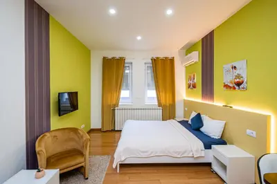 a bedroom with yellow walls and a bed and a tv at Kalanj Apartmani I Sobe in Belgrade