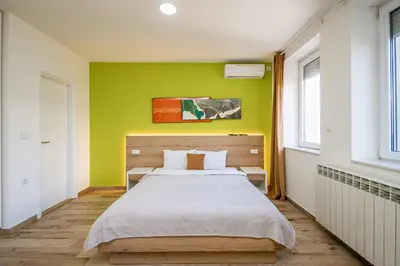 a bedroom with a bed and a green wall at Kalanj Apartmani I Sobe in Belgrade