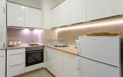 a kitchen with white cabinets and a sink and a refrigerator at Apartman Tirena in Belgrade
