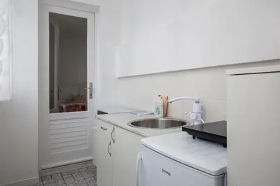 a white kitchen with a sink and a refrigerator at Apartment Slavija square/Clinical center of Serbia in Belgrade