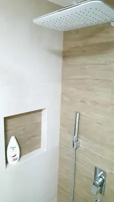 a bathroom with a shower with a wooden wall at Arena Relax Apartman in Belgrade