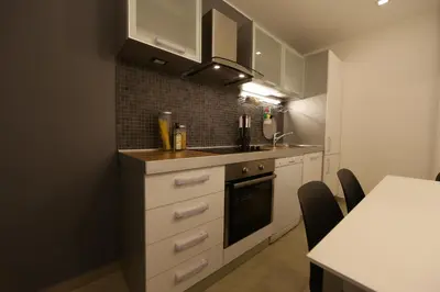 a kitchen with white cabinets and a sink and a table at Apartment Piano in Belgrade