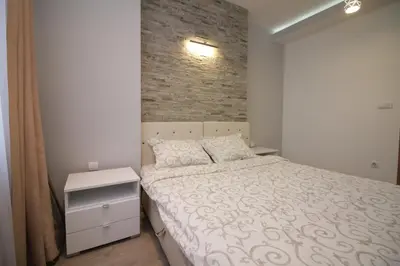 a bedroom with a bed and a brick wall at Diva Lux Apartman in Belgrade