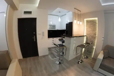 a kitchen and living room with a bar counter and stools at Diva Lux Apartman in Belgrade