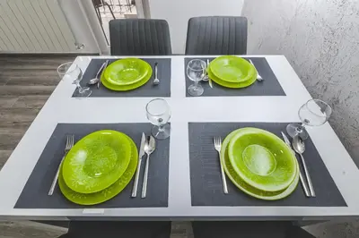 a white table with green plates and silverware on it at Kristal Apartmani in Arandjelovac