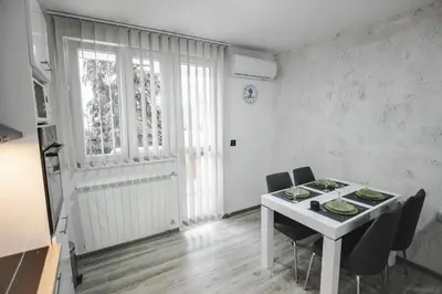 a white dining room with a white table and chairs at Kristal Apartmani in Arandjelovac