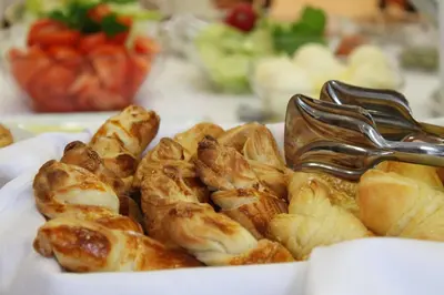 a plate of food with croissants and a fork at Hotel Rex in Belgrade
