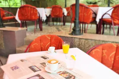 a table with a newspaper and a glass of orange juice at Hotel Rex in Belgrade