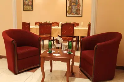 a dining room with two chairs and a table with bottles on it at Hotel Rex in Belgrade