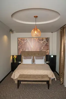 a bedroom with a large bed with a bench in it at Akacija Luxury Suites- Zemunski kej in Belgrade
