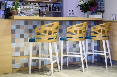 a bar with three stools in front of a counter at Garni Hotel D10 in Belgrade