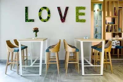 a room with two tables and stools with a love sign on the wall at Garni Hotel D10 in Belgrade