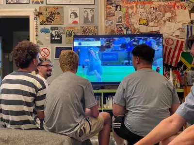 a group of men sitting on a couch playing a video game at Habitat Hostel in Belgrade