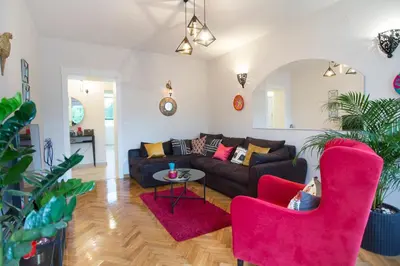 a living room with a black couch and pink chairs at City Side Up Exclusive in Belgrade