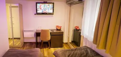 a room with a desk and a television on the wall at Olympic Wellness & Spa Apartments in Belgrade