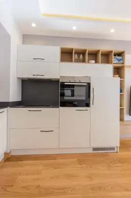 a kitchen with white cabinets and a microwave at Sava Smart Apartment in Belgrade