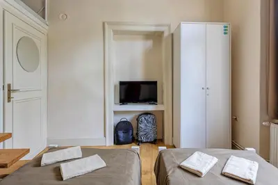 a bedroom with two beds and a tv and a cabinet at Booking BnB in Belgrade