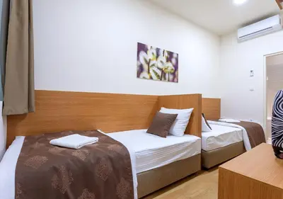 a bedroom with two beds and a desk with a television at Booking En Suite in Belgrade