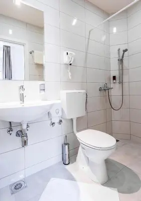 a white bathroom with a toilet and a sink at Booking En Suite in Belgrade