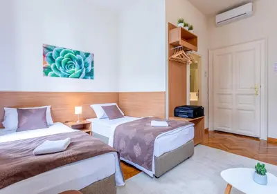 a small room with two beds and a table at Booking En Suite in Belgrade