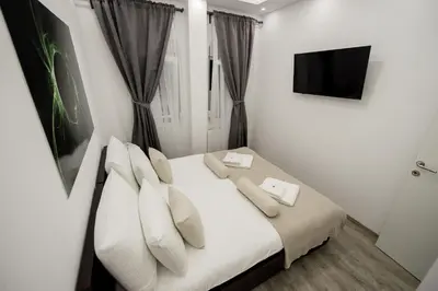 a bedroom with a bed with white pillows and a tv at CENTAR Lux in Arandjelovac