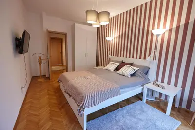 a bedroom with a bed with a striped wall at Take 5 in Belgrade