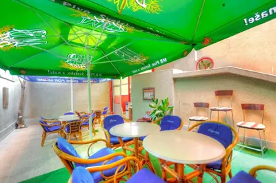 a restaurant with tables and chairs and green umbrellas at Villa Forever in Belgrade