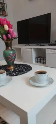 a table with a vase of flowers and two cups of coffee at Cute little apartment in Belgrade