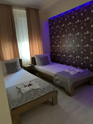 a room with two beds and a bench and purple lighting at Apartmani CENTAR- Smederevo in Smederevo