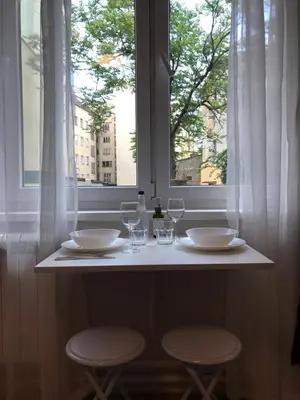 a table with two chairs and glasses and a window at Apartman Mia in Belgrade