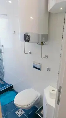 a bathroom with a white toilet and a blue floor at Apartman Mia in Belgrade
