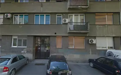 two cars parked in a parking lot in front of a building at Apartman Mia in Belgrade