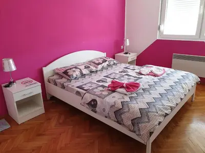 a bedroom with a bed with a pink wall at Apartment Centar Deluxe in Smederevo