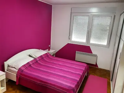 a pink bedroom with a bed and a window at Apartment Centar Deluxe in Smederevo
