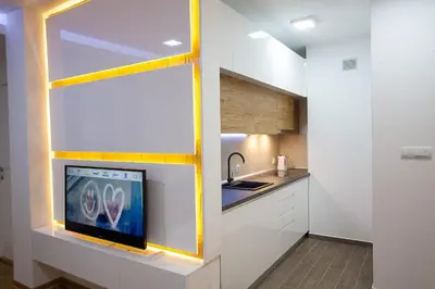 a kitchen with a tv on a wall at White Lux apartment in Belgrade