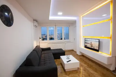 a living room with a black couch and a large window at White Lux apartment in Belgrade