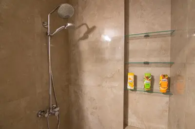 a shower with two bottles of cleaner on a glass shelf at St. Sava Temple/Slavija square in Belgrade