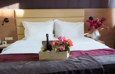 a bed with a bottle of wine and flowers on it at Hotel Srbija Garden-FREE PARKING-upon availability in Belgrade