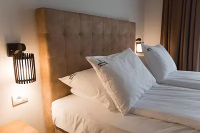 a bed with white pillows on it in a room at Hotel Borkovac in Ruma