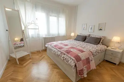a white bedroom with a bed and a mirror at Belgrade Center Apartment II in Belgrade