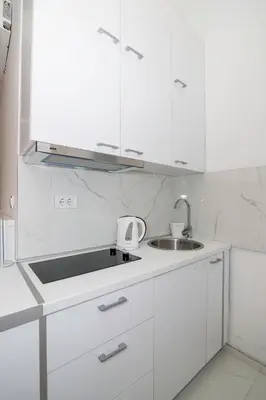 a white kitchen with a sink and white cabinets at Royal park in Belgrade