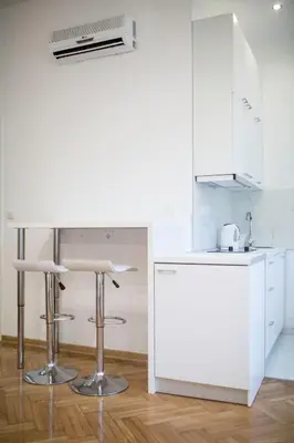 a kitchen with white cabinets and bar stools at Royal park in Belgrade