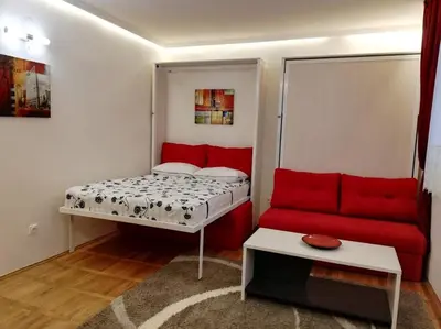 a small room with a bed and a red couch at Lola 1 in Belgrade