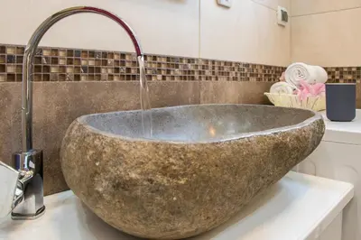 a bathroom with a large stone sink with a faucet at Belgrade Downtown Residence in Belgrade