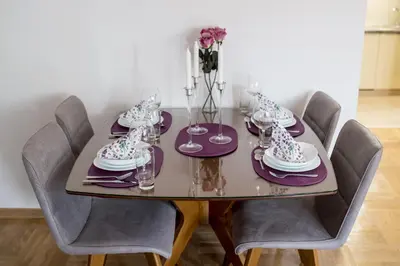 a dining room table with purple chairs and a table with glasses at Central Park Lux in Arandjelovac