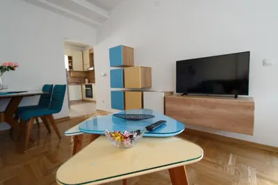 a living room with a table and a tv at Central Park Lux in Arandjelovac