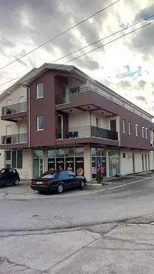 a large building with cars parked in front of it at Prenočište Dunav in Novi Banovci