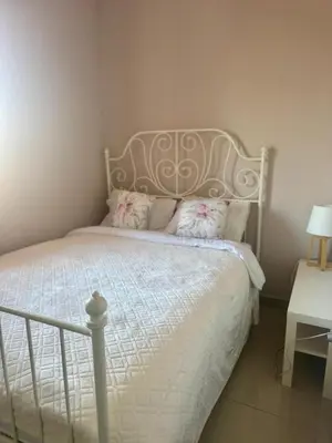 a bedroom with a white bed with a metal headboard at Prenočište Dunav in Novi Banovci