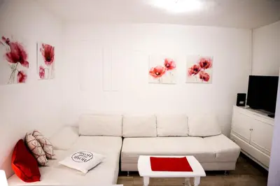 a white living room with a white couch and red accents at Gardos in Belgrade