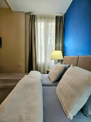 a bedroom with two beds and a blue wall at Male stepenice in Belgrade